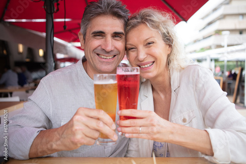 happy mature couple toasting sat in restaurant terrace
