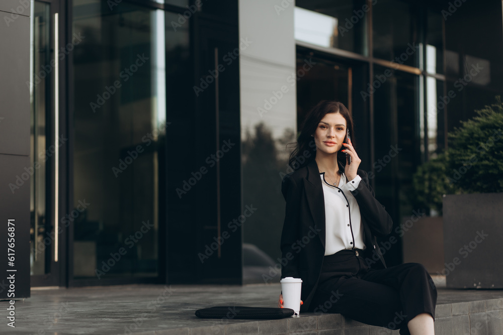 Attractive young businesswoman in white suit talking phone standing near business centre Attractive young businesswoman in white suit talking phone standing near business centre
