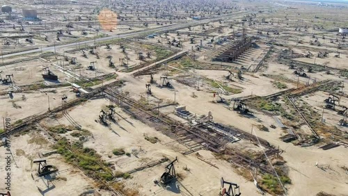 Pumping crude oil at oil wells in the fields for high demand fossil fuels - aerial flyover