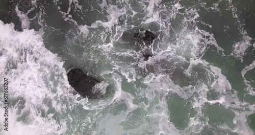 Drone moving away from ocean waves and colliding with rocks photo