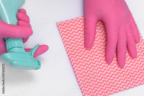 Dłonie w różowych gumowych rękawicach ochronnych i płyn do czyszczenia mebli 