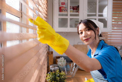 Asian young woman cleaning window in the kitchen. housework concept