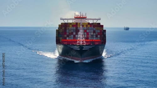 Front view of a very large container cargo ship traveling with speed over blue ocean