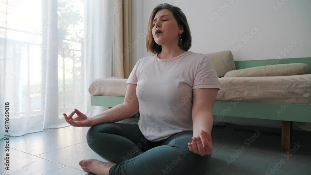 Plus size woman practice yoga in lotus pose at home. Healthy lifestyle and fitness for overweight people concept.
