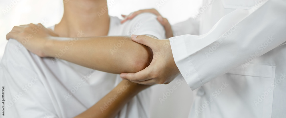 Female physiotherapists provide assistance to male patients with elbow injuries and examine patients in rehabilitation centers. Physiotherapy concepts Female physiotherapists provide assistance to male patients with elbow injuries and examine patients in rehabilitation centers. Physiotherapy concepts