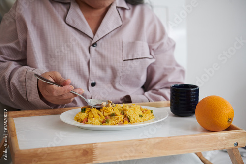Senior woman eating lunch in her bed receving from illness