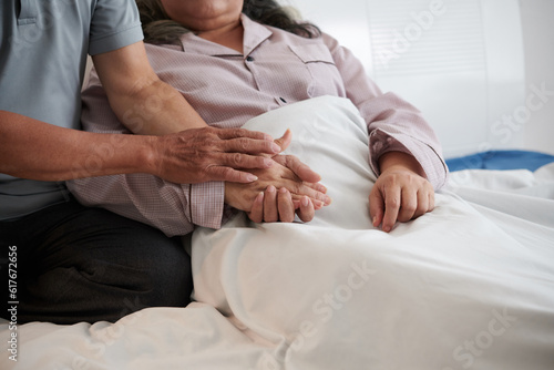 Husband holding hand of sick wife to support her