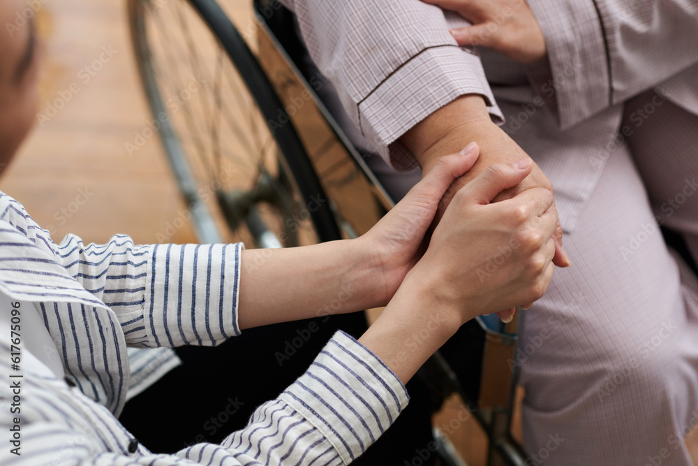 Caregiver holding hand of senior patient to support her