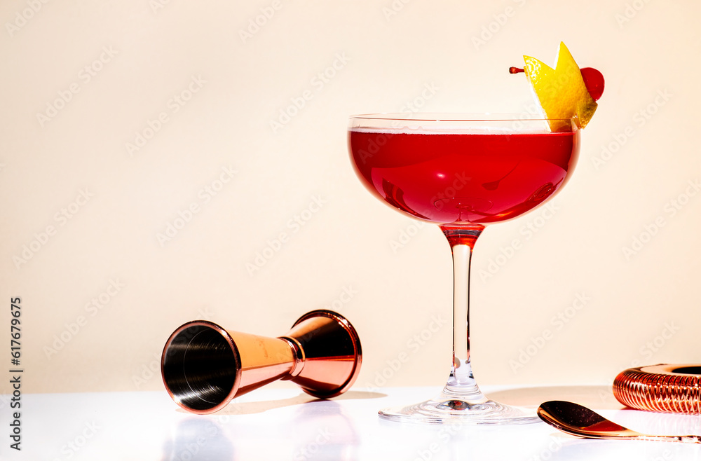 New Yorker red cocktail with whiskey, grenadine, bitter, lemon and ice garnished with lemon zest and cocktail cherry in glass. Beige background, hard light - obrazy, fototapety, plakaty 