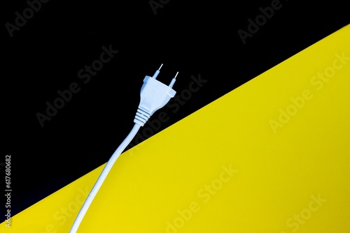 Closeup shot of a white electrical plug with a wire on a yellow black surface