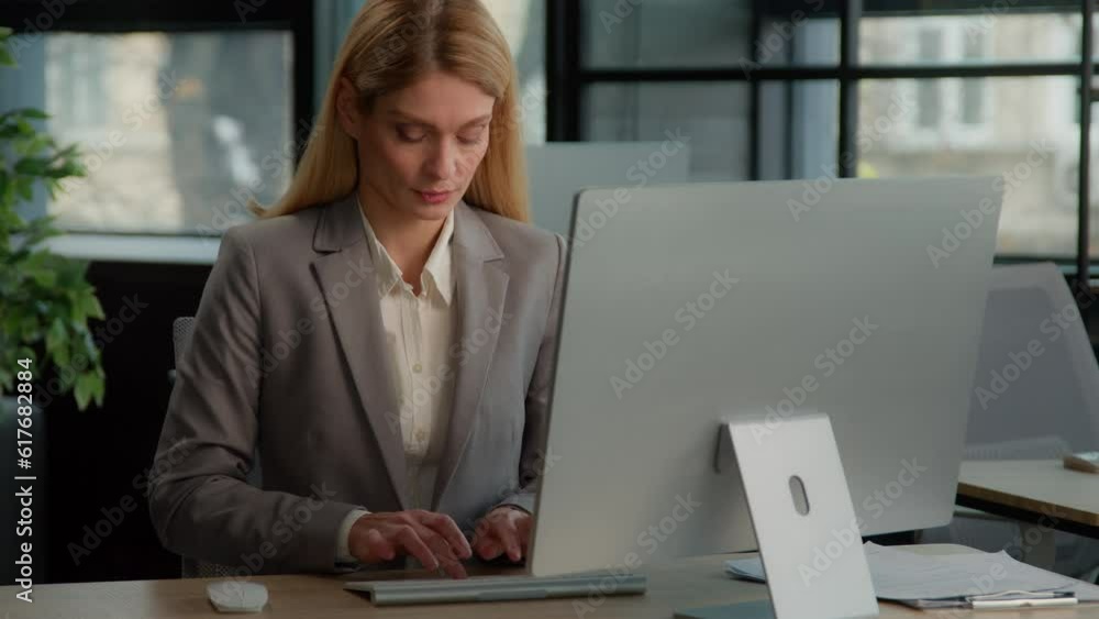 Caucasian middle-aged woman in office working with online project. Business female work in Internet communicate with clients distant with computer corporate company job businesswoman employer typing Caucasian middle-aged woman in office working with online project. Business female work in Internet communicate with clients distant with computer corporate company job businesswoman employer typing