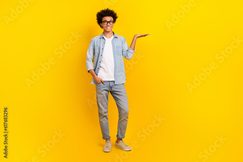 Full body photo of positive person hand palm hold demonstrate empty space isolated on yellow color background