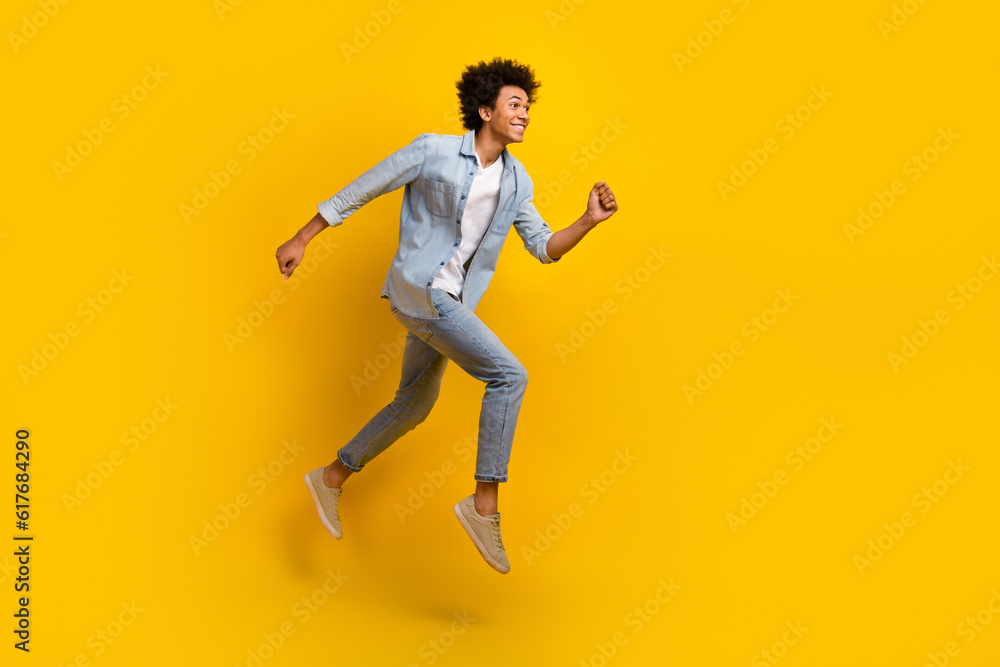 Full size photo of nice optimistic guy wear jeans jacket pants excited running shopping on big sale isolated on yellow color background