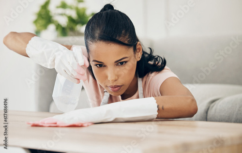Woman, chemical spray and cleaning wooden table, hygiene with household maintenance and detergent. Female cleaner, disinfectant and wipe or clean dirt with cloth from surface and janitor service
