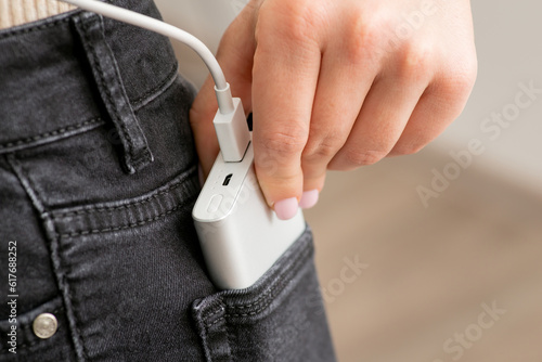 Power bank in the back pocket of girl's jeans, close up. Concept of using modern technologies, charging gadgets, convenient and portable devices