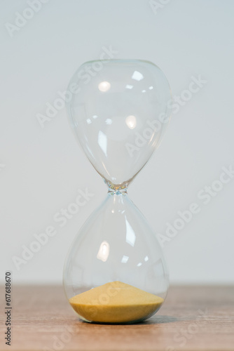 Vertical shot of small sandglass standing on the table, close up. All sand in the bottom, the end of some time period, the time is up