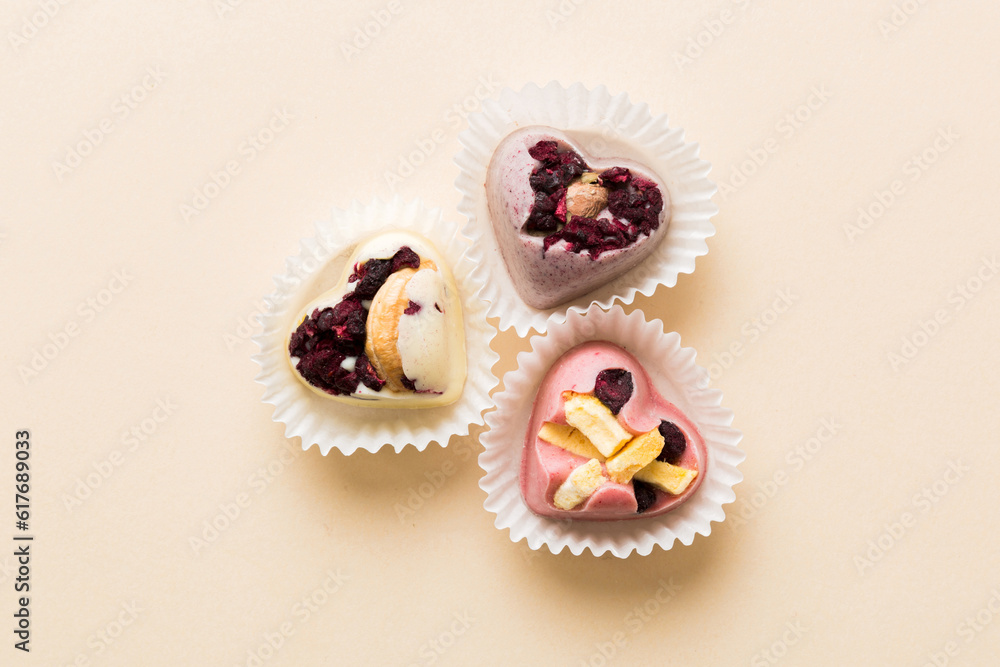 chocolate sweets in the form of a heart with fruits and nuts on a colored background. top view with space for text, holiday concept chocolate sweets in the form of a heart with fruits and nuts on a colored background. top view with space for text, holiday concept