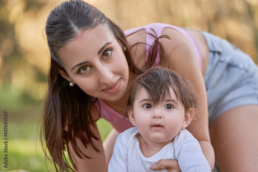 portrait of a young brunette woman with her baby in her hands looking at the camera in the park portrait of a young brunette woman with her baby in her hands looking at the camera in the park