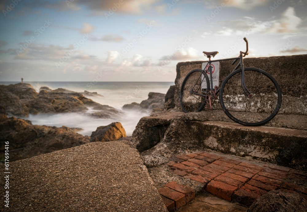 Fototapeta premium Old bike leaning against a seawall on the Gold Coast, Qld, Australia.