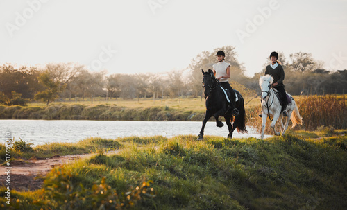 Horse riding, freedom and equestrian with friends in nature on horseback by the lake during a summer morning. Countryside, hobby and female riders outdoor together for travel, fun or adventure © Kirsten Davis/peopleimages.com