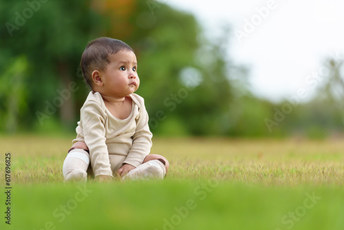 infant baby sitting on green grass field at the park