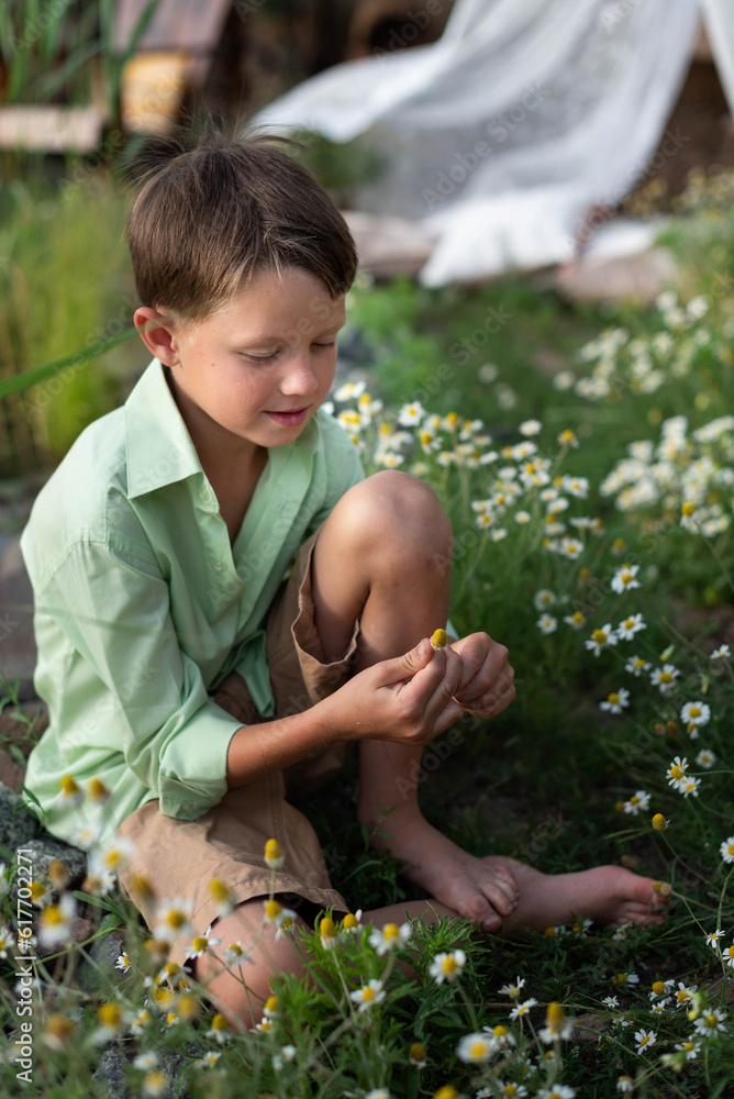 A child boy is sitting on the grass in the backyard A child boy is sitting on the grass in the backyard