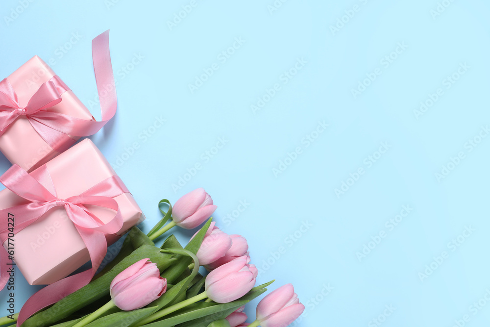 Beautiful gift boxes and pink tulip flowers on light blue background, flat lay. Space for text Beautiful gift boxes and pink tulip flowers on light blue background, flat lay. Space for text