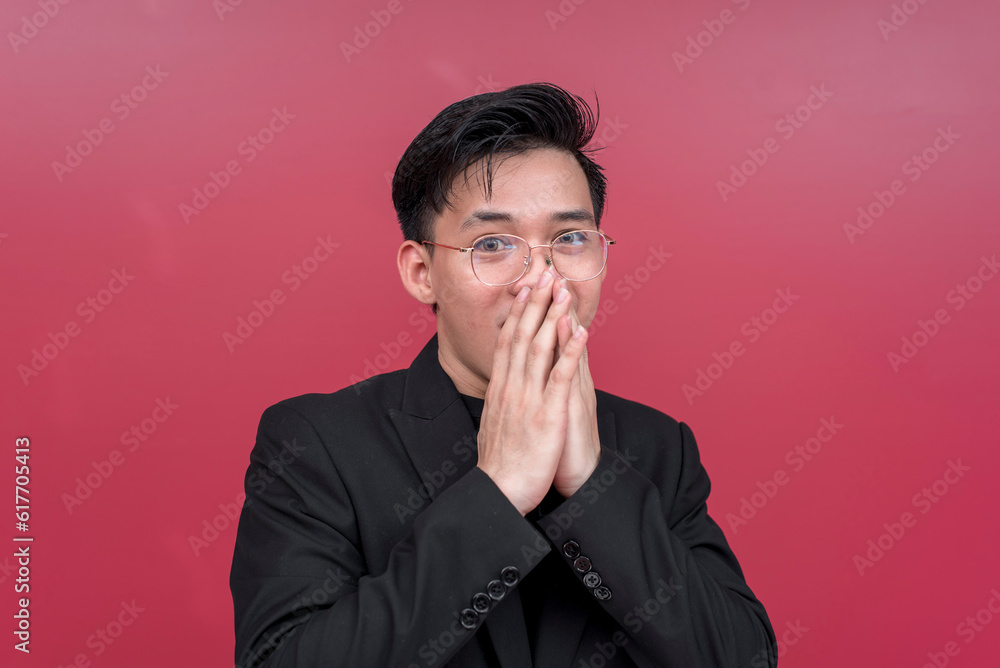 Portrait of a shocked young man wearing glasses with both hands on his mouth. Isolated on a red background. Portrait of a shocked young man wearing glasses with both hands on his mouth. Isolated on a red background.