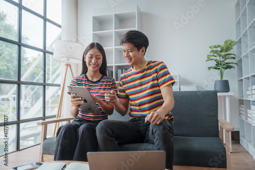 Happy married asian chinese couple sit at home office by paperwork business accounting. Glad young spouses read financial report get profit tax refund