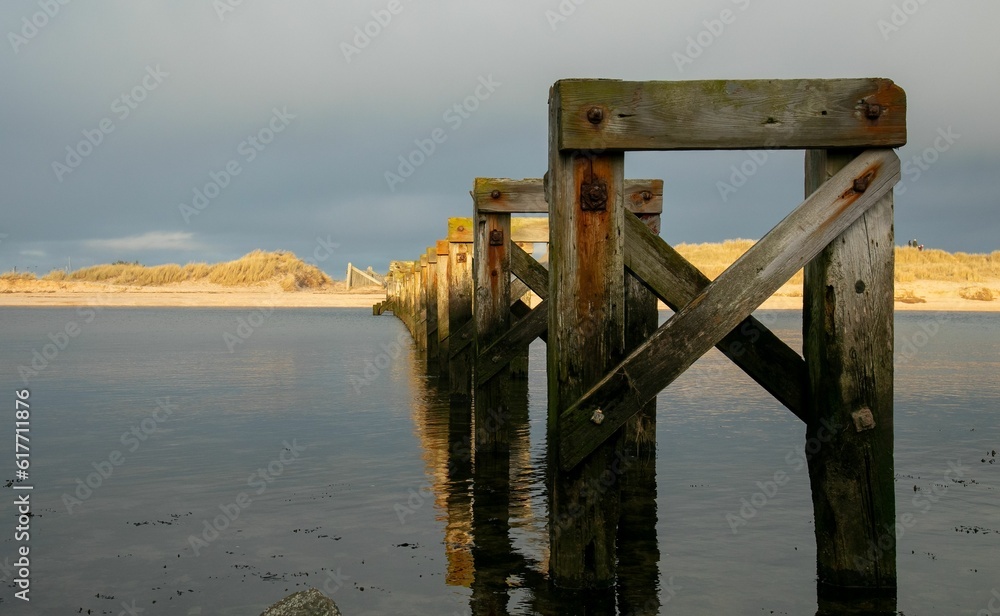 Tranquil body of water, featuring an abandoned wooden bridge foundation Tranquil body of water, featuring an abandoned wooden bridge foundation