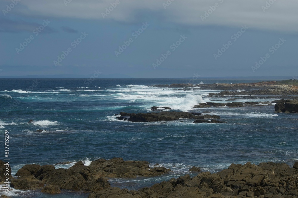 Waves splashing on the rocks of the coast against the blue sky