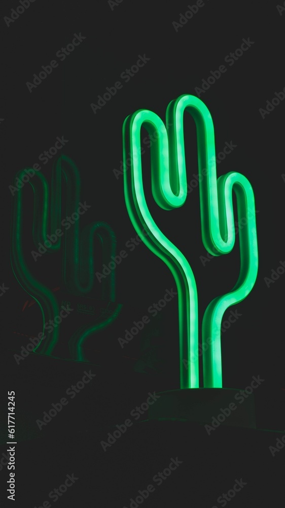 Vertical shot of a glowing neon cactus light illuminated in a dark room Vertical shot of a glowing neon cactus light illuminated in a dark room