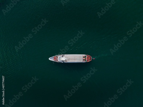 An aerial top view of an industrial ship sailing in dark green water