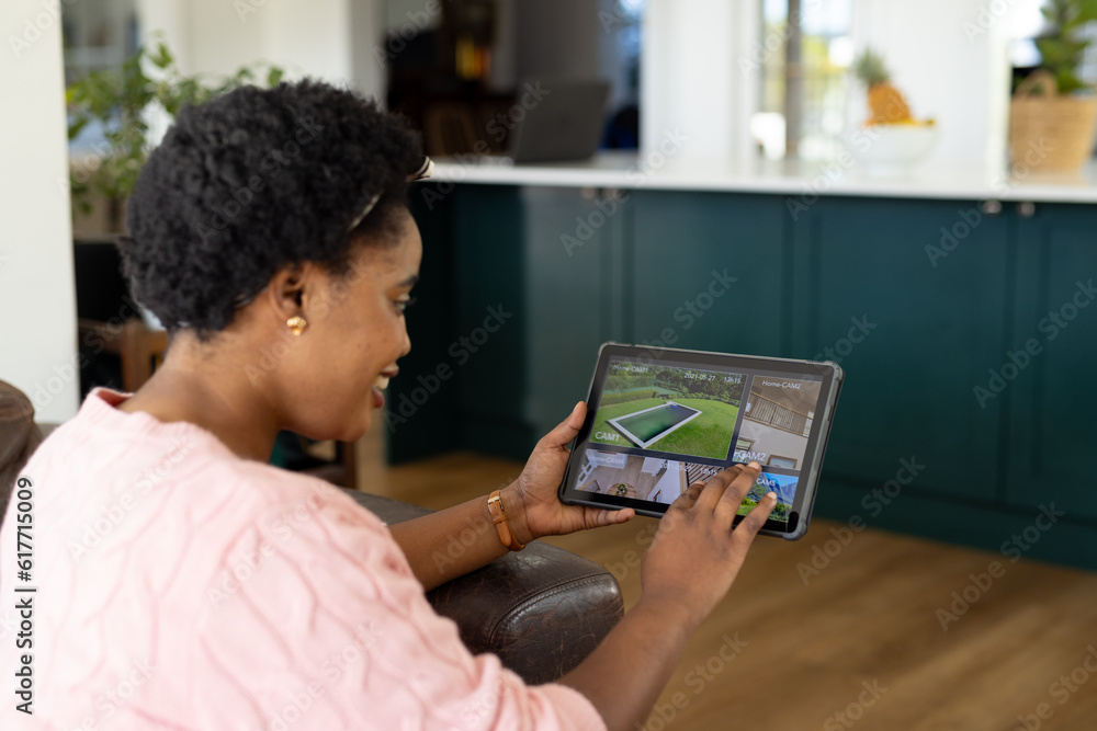 Happy plus size african american woman using tablet with home security camera views on screen Happy plus size african american woman using tablet with home security camera views on screen