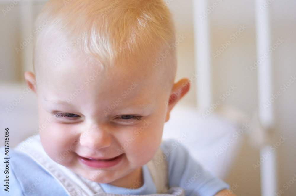 Funny, children and baby in the crib of a nursery in his home for growth, child development or curiosity. Kids, laughing and toddler with a male or boy child standing in his cot looking adorable