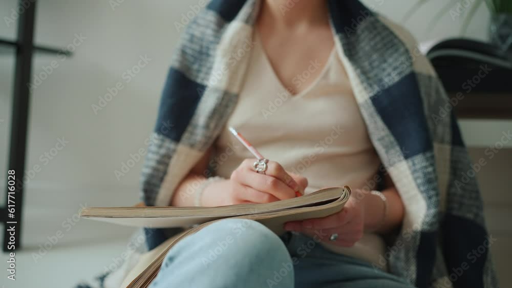 Woman covered with blanket drawing in notebook at home Woman covered with blanket drawing in notebook at home