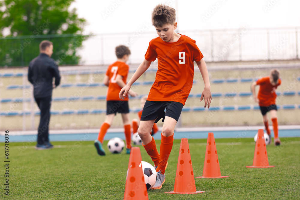 Happy Boy on Soccer Training Slalom Drill. Boys Practicing European Soccer on the Grass School Field. Soccer Training - Warm Up and Slalom Drills