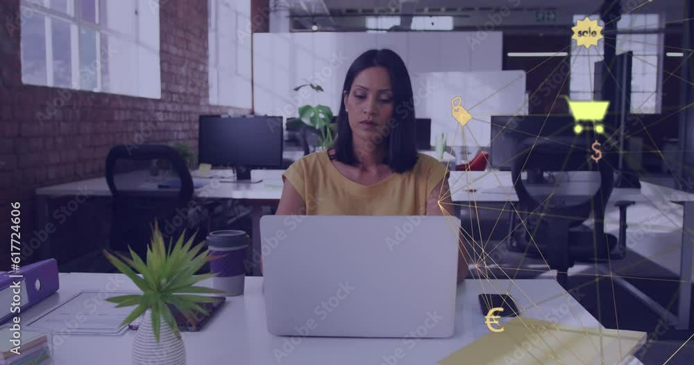 Animation of globe of digital icons spinning over thoughtful biracial woman using laptop at office Animation of globe of digital icons spinning over thoughtful biracial woman using laptop at office