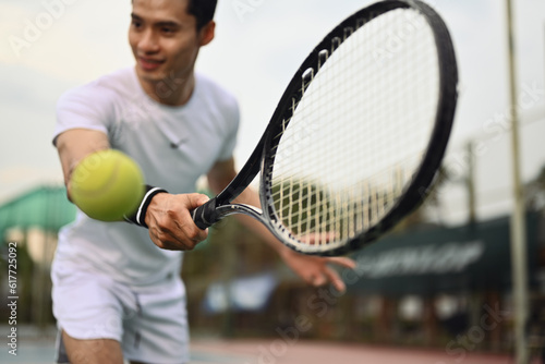 Shot of male tennis player hitting ball with racket. Sport, fitness, training and active life concept © Prathankarnpap