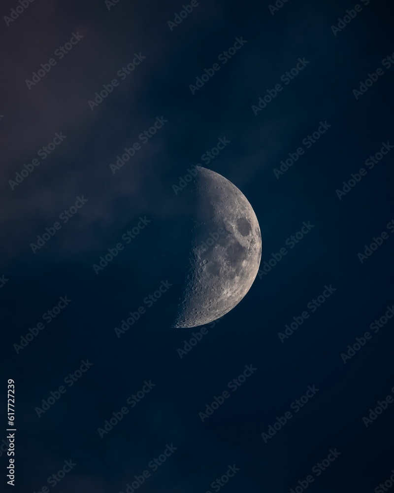 Large half moon partially obscured by clouds in the night sky with a blurred background