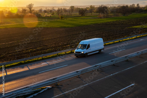 White delivery van on the highway. White modern delivery small shipment cargo courier van moving fast on motorway road to city urban suburb. The world's best transport of goods.