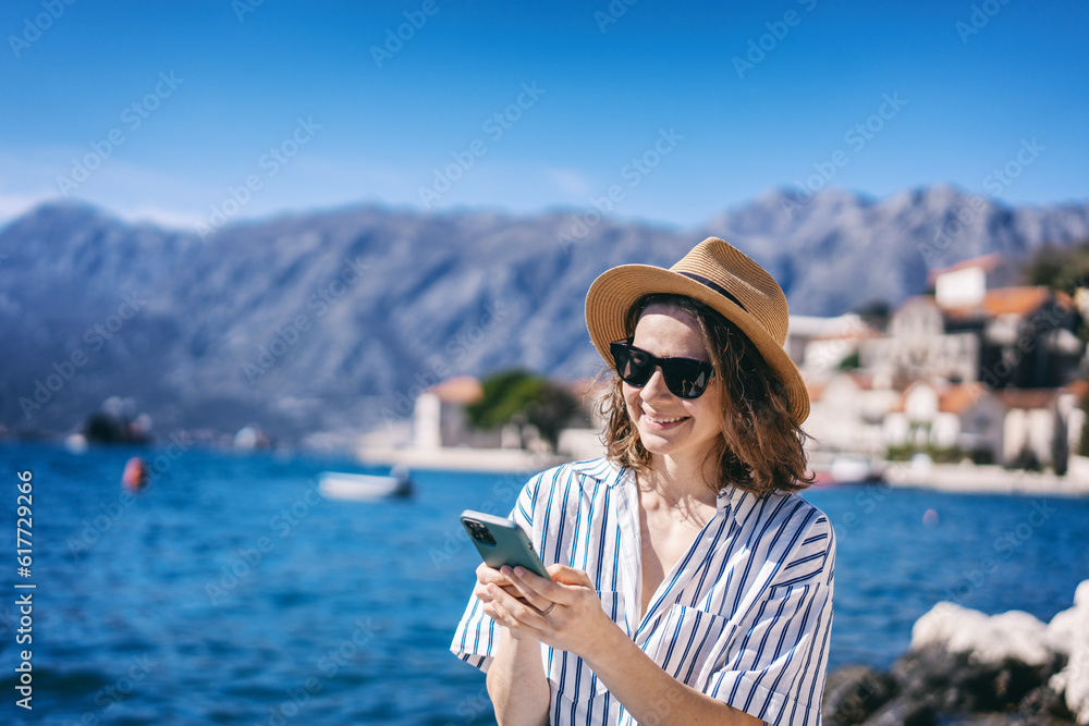 Young smiling woman using a smartphone on the shore of a mediterranean resort