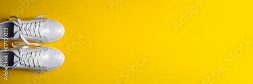 White leather shoes on a yellow background. White sneakers with white laces. New shoes. Horizontal image. Banner for insertion into site.