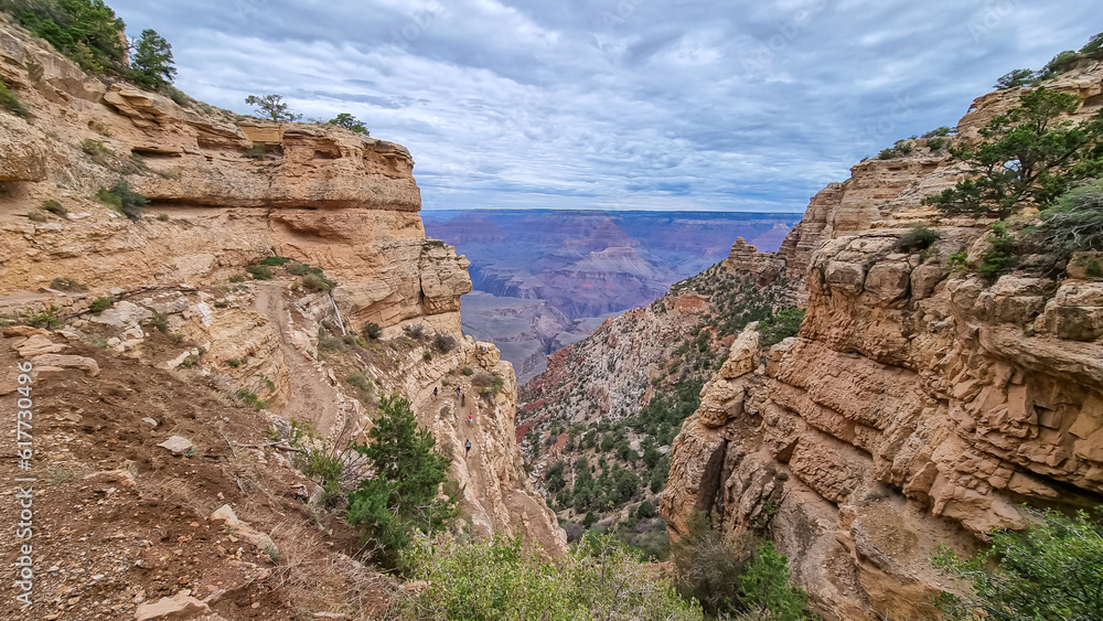 Panoramic aerial view from Bright Angel hiking trail at South Rim of Grand Canyon National Park, Arizona, USA. Vista on Indian Garden and Colorado River weaving through valleys and rugged terrain