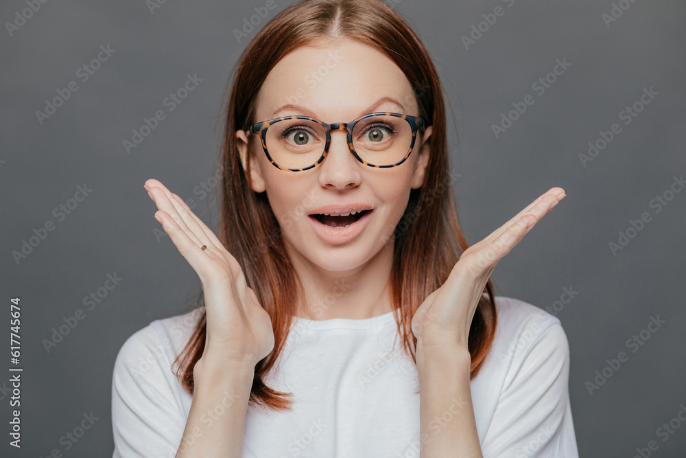 Surprised woman, pleasant appearance, palms near face. Mouth open in wonder. Casual t-shirt. Isolated on grey. Surprised woman, pleasant appearance, palms near face. Mouth open in wonder. Casual t-shirt. Isolated on grey.