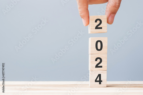 hand holding wooden cube block with 2024 text on table background. Resolution, plan, review, goal, start and New Year holiday concepts