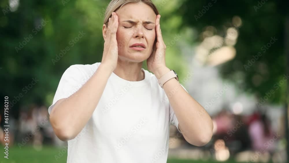 Unhappy blond mature woman freelancer with closing eyes suffering headache painful feelings chronic migraine high or low pressure after hard laptop computer work at green park Unhappy blond mature woman freelancer with closing eyes suffering headache painful feelings chronic migraine high or low pressure after hard laptop computer work at green park