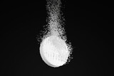 Dispersible aspirin sinking and dissolving into clear water on black background. Illustration of the concept of soluble pills and pharmaceutical industry