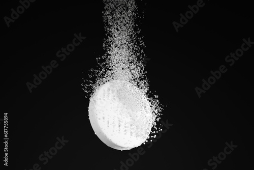 Dispersible aspirin sinking and dissolving into clear water on black background. Illustration of the concept of soluble pills and pharmaceutical industry photo