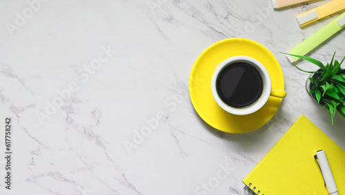Top view image of ceramic coffee cup, potted plant, note, pen and marker pens putting together on marble texture table. Creative workplace concept.
